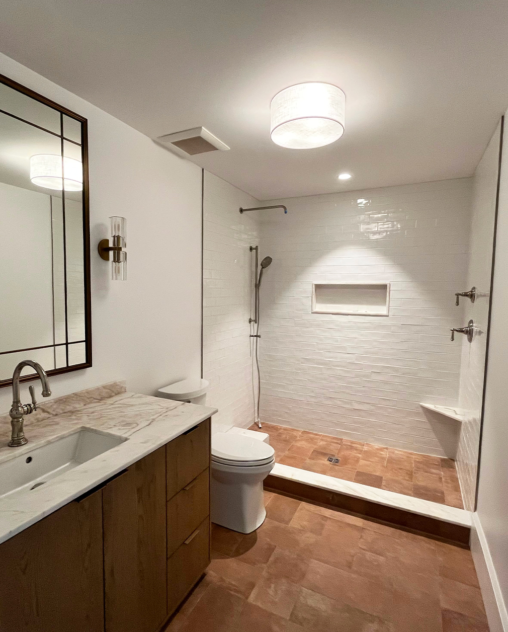 A floating marble vanity against white-oak paneling in a freshly finished powder room.
